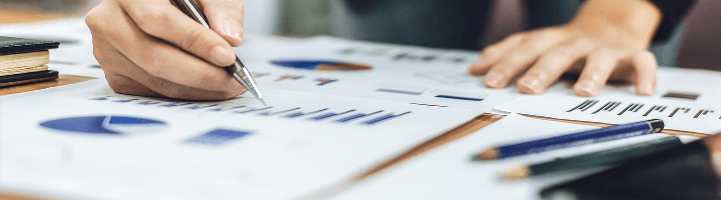 Person writing on a page with graphs.